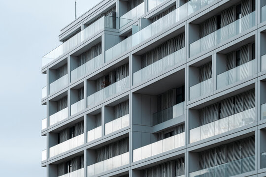 Contemporary apartment facade architecture with modern residential windows and balcony forming repeating pattern for real estate marketing showing exterior detail