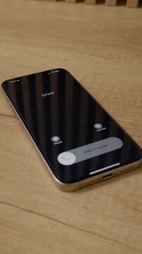 Vertical Screen: A smartphone sits on a wooden table showing an incoming call from spam. The phone alerts the user of a potential scam on the screen.