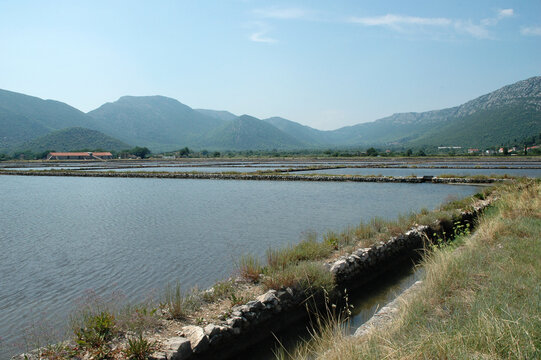 The ancient stone basins of the Ston salt pans are filled with sea water beneath green hills on the Peljesac peninsula