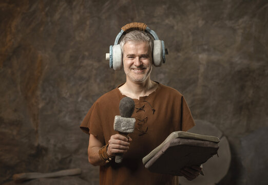 Funny Prehistoric Caveman Broadcasting with Primitive Stone Headphones and Microphone - Ancient Media Concept