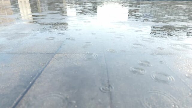 Raindrops hit wet pavement, creating ripples