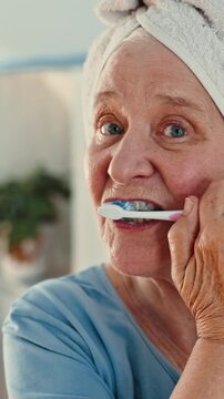 Face, elderly or woman brushing teeth with toothbrush in bathroom for dental hygiene or cleaning. Portrait, senior or female person with towel or tooth whitening for oral, mouth or gum care in home