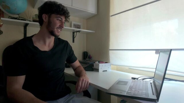 Young man speaks sign language on a video call on a laptop indoors. 
