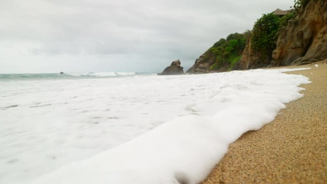 Incoming tide washes over a solitary footprint on the sandy beach of Playa Los Angeles in Los Naranjos Cove, Santa Marta, Colombia. A peaceful scene of nature erasing a human mark