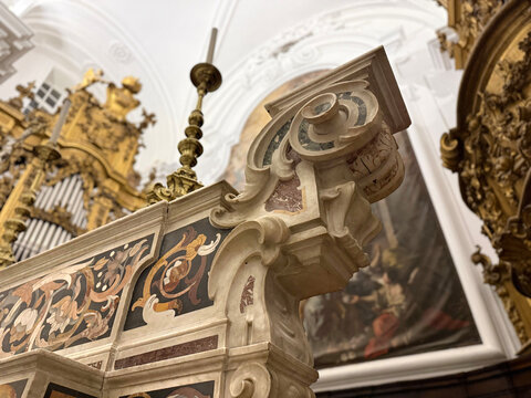 CAPUA, ITALY - NOV 2025: Close-up of the high altar at the Church of Saint Mary of the Announcement, showcasing intricate polychrome marble inlay and a Baroque volute scroll.