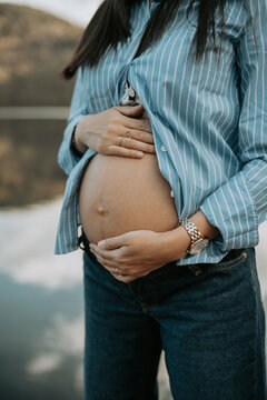 Femme enceinte tenant son ventre nu avec tendresse lors d'une s&eacute;ance photo de maternit&eacute; 