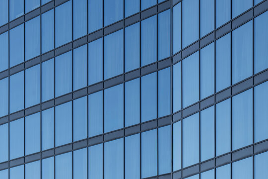 Modern architecture facade of blue glass building with curved lines creating abstract pattern on a sleek contemporary urban exterior detail