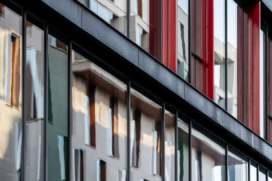Modern architecture facade with red color accents on building windows where lines and pattern guide perspective in contemporary urban exterior detail