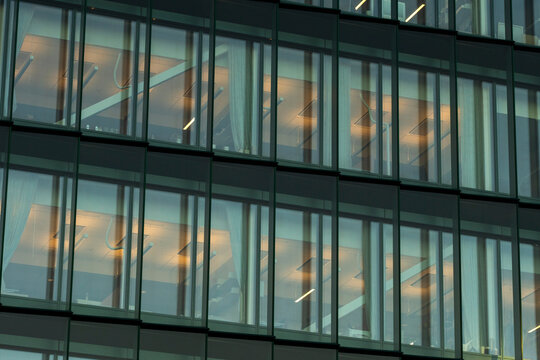 Modern office architecture facade with glass windows and grid pattern revealing interior light inside contemporary building exterior detail