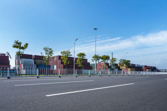 Empty Urban Roadway Bordering Container Yard Under Bright Blue Sky