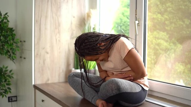 African american teenage girl suffering from stomach ache at home