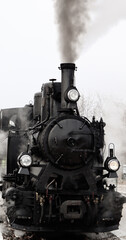 Classic black steam train engine on tracks with smoke coming out © Zsuzsanna
