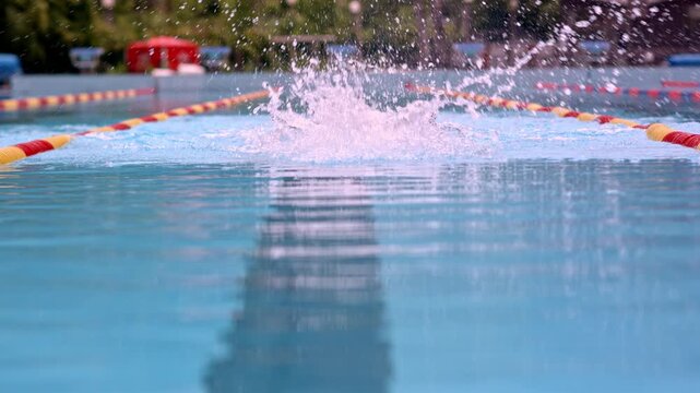 The shot is a medium close-up with a side view capturing a swimmer performing a freestyle stroke. The, likely a male, is in a pool during sports training, wearing a swim cap and goggles.