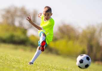 Fototapeta premium Young boy kicking soccer ball