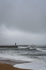 Fototapeta premium Stormy Atlantic ocean with powerful waves hitting coastline in Porto Portugal. Dramatic seascape with dark clouds, rough sea and coastal pier during bad weather conditions.