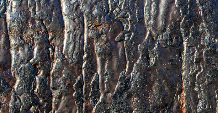 Dark weathered metal surface with melted resin texture and thick black paint coating
