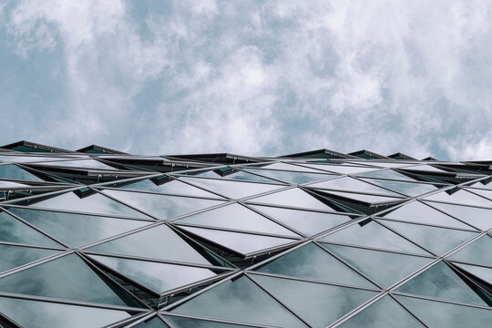 Modern architecture facade of geometric glass pattern uses perspective lines as sky clouds open generous copyspace for advertising headline space