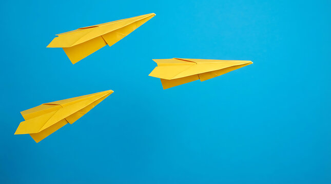 Three yellow paper planes flying on a solid blue background