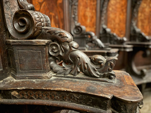 CAPUA, ITALY - NOV 2025: Close-up of a wood-carved armrest in the choir stalls at the Church of Saint Mary of the Announcement, featuring a putto riding a mythical creature. 3/4