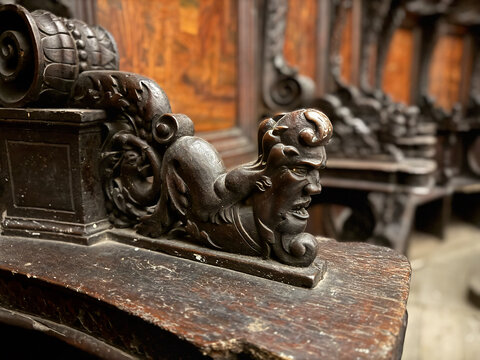 CAPUA, ITALY - NOV 2025: Close-up of a wood-carved armrest in the choir stalls at the Church of Saint Mary of the Announcement, featuring a putto riding a mythical creature. 4/4