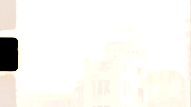 Super 8 mm retro vintage film of hanging leaves in front of the Genbaku Dome structure ruins and historic public monument landmark near Peace Memorial Park in Hiroshima Japan Asia tourism and culture