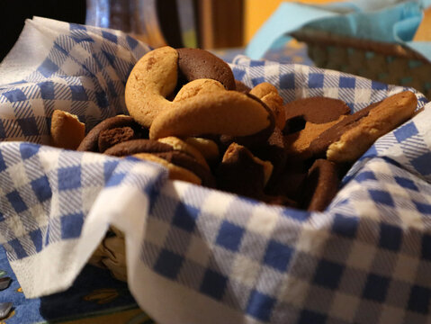 Cestino foderato con tovagliolo a quadretti bianchi e azzurri riempito di biscotti artigianali assortiti alla vaniglia e al cioccolato a forma di mezzaluna, ideali da servire con il Bicerin.