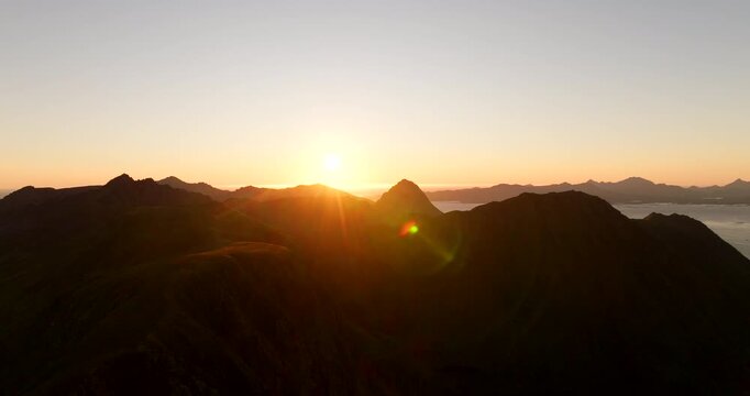 Scenic golden hour sunset over Storheia mountain peaks in Stokmarknes, aerial