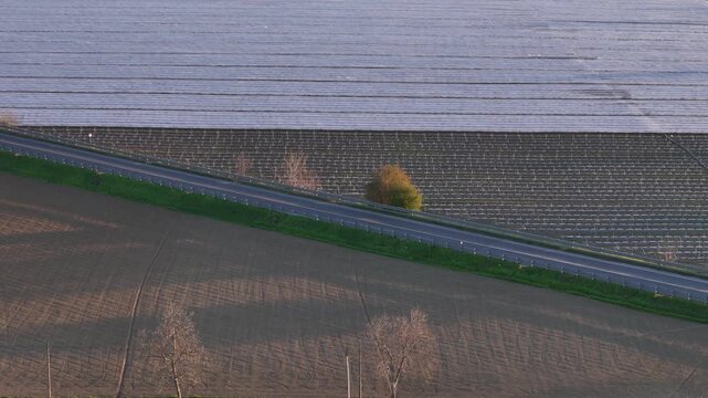 Low tunnel intensive cultivation near Alseno Piacenza Emilia Romagna Italy along SS9 Via Emilia with parallel plastic covered rows melon crops in Pianura Padana agricultural system, aerial pull back