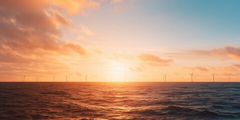 Fototapeta premium Wind turbines stand tall against the sunset on the ocean horizon in early evening light