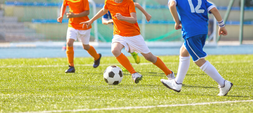 Children Playing Football Toruanment Game. Happy Kids Kicking Soccer Ball. Group of School Kids Playing Soccer at Grass Field. Sports Venue in the Background