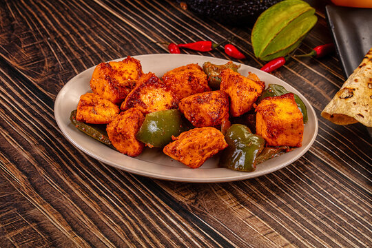 Indian Paneer Tikka Masala inl with Roti bread on a dark wooden table