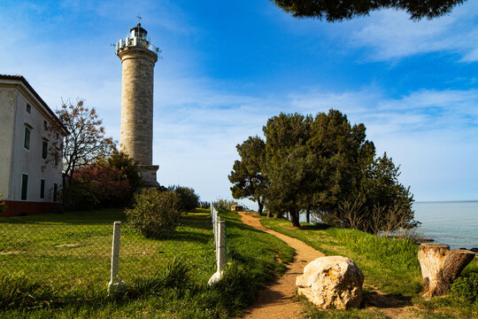 Savudrija Lighthouse (Istria, Croatia) at sunset on the Adriatic coast, historic stone tower by the sea, dramatic sky, waves, and scenic Croatian coastline.