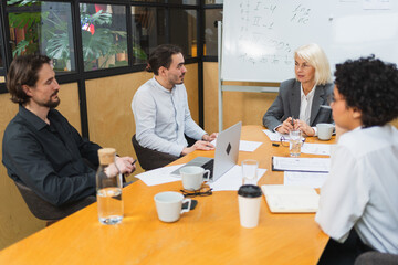 Fototapeta premium Teamwork brainstorm. Coworkers cooperating working together at office meeting. Colleagues discussing project ideas. Group of people in creative office discussing business. Young professional team