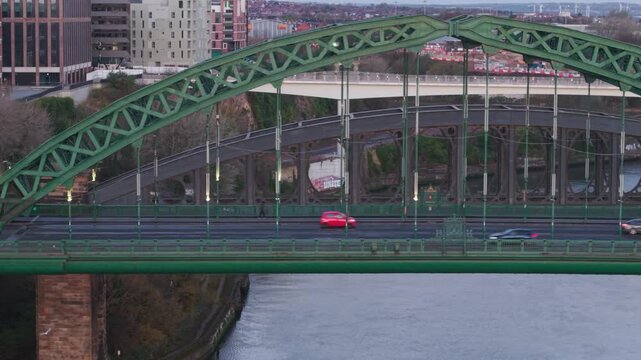 Telephoto clip as drone tracks sideways beside the Wearmouth Bridge in Sunderland as early morning traffic commutes to the city