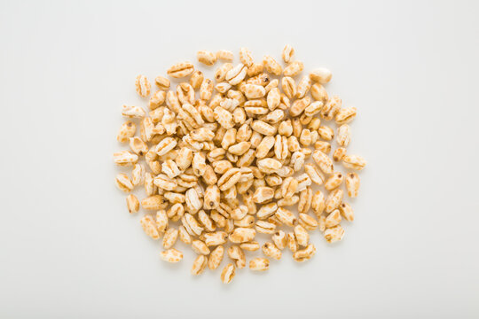 Heap of yellow dry puffed wheat flakes on light gray table background. Closeup. Top down view.