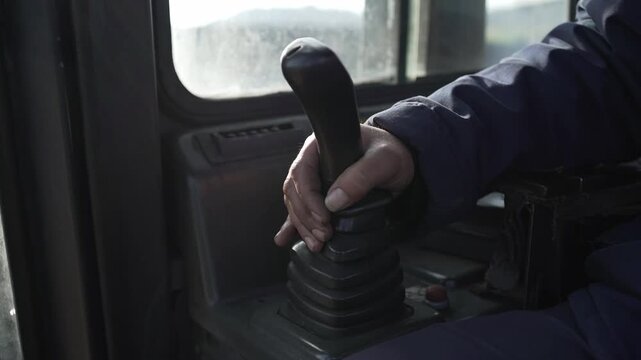A worker controls a bulldozer using a joystick.