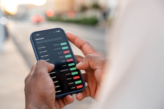 Person trading cryptocurrency on smartphone, viewing market data and digital assets