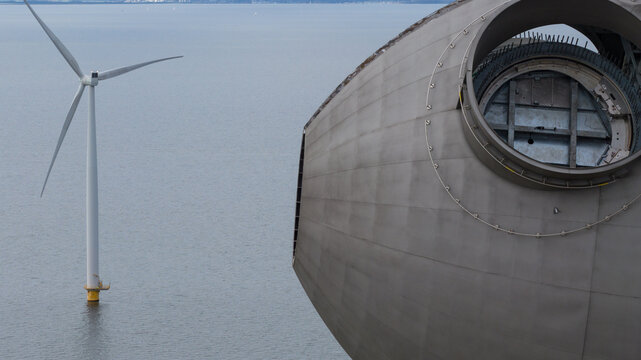 Aerial view of the Westermeerdijk wind farm showing a close-up of a turbine nacelle and another turbine in the water Espel, Flevoland, Netherlands.