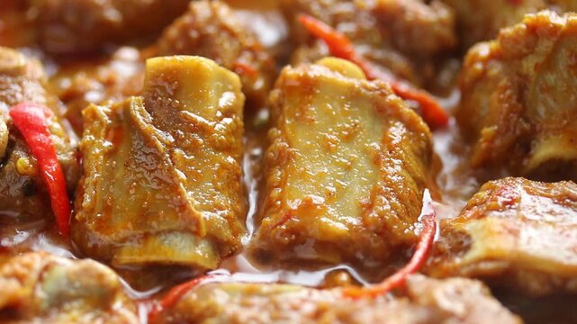 Stir-frying pork ribs with Thai red curry paste in a hot pan. Close-up