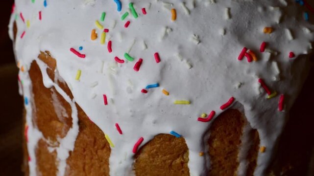 a traditional easter cake with white icing and colorful sprinkles, featuring a slow zoom-out that reveals the full pastry surrounded by dyed easter eggs