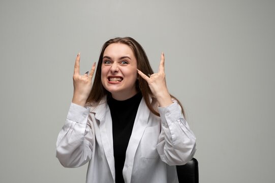 Young woman making rock and roll hand gestures while grimacing, showing excitement and expressive emotion