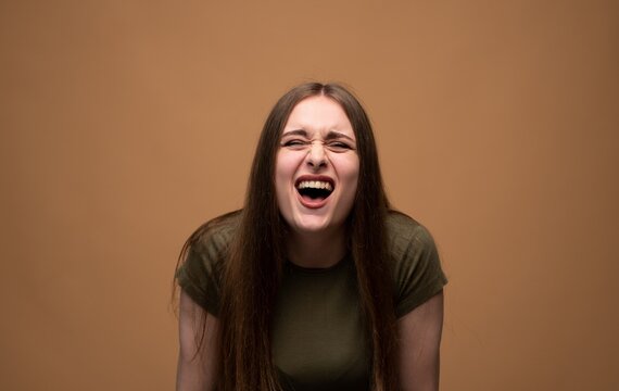 Woman expressing intense anger and frustration, screaming with eyes closed, experiencing emotional stress