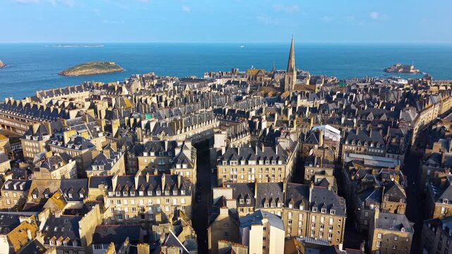 Historic ramparts and dense architecture of walled city, Intra-Muros of Saint-Malo in Brittany, France. Aerial drone backward
