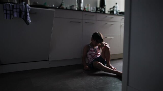 Child isolated on kitchen floor surrounded by empty space with body curled inward expressing emotional suffering depression and loneliness highlighting impact of childhood trauma