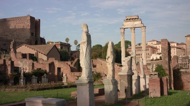 Ancient marble statues at House of the Vestals with Temple of Castor and Pollux columns in Roman Forum, historic ruins and classical architecture in Rome Italy