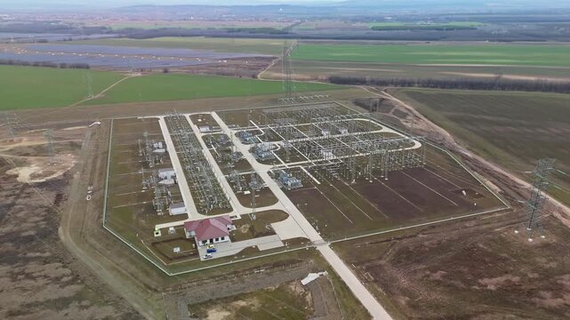 G&ouml;d, Hungary&rsquo;s MAVIR G&ouml;d Kelet substation features modern high-voltage transformers, pylons, and powerlines distributing electricity across fields, captured in an orbital drone view.