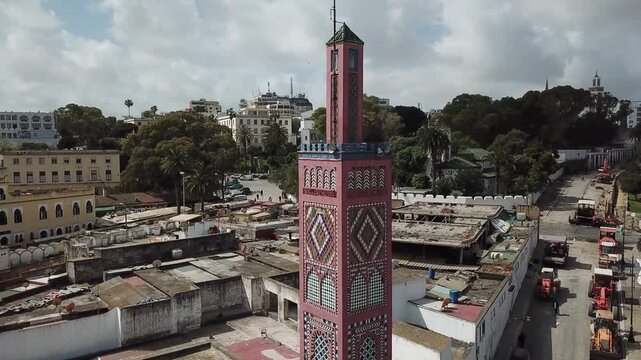 Detailed drone shot of a colorful decorated minaret in Tangier, Morocco, featuring traditional tile patterns and a surrounding urban cityscape.