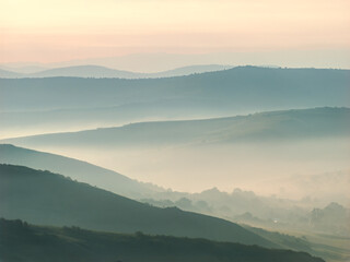 Obraz premium Layered mountain hills in mist at sunrise atmospheric landscape