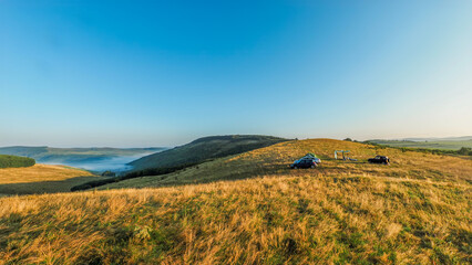 Fototapeta premium Summer hillside landscape with camping tent and car in nature