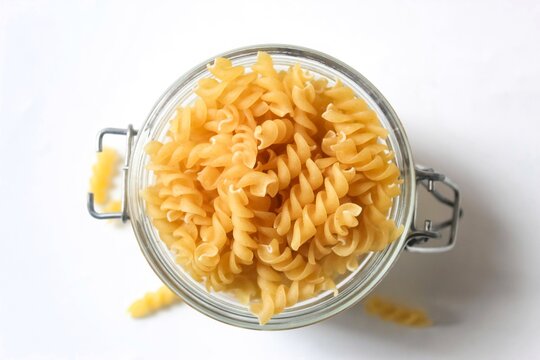 top view of fusilli pasta in a glass jar isolated on a white background